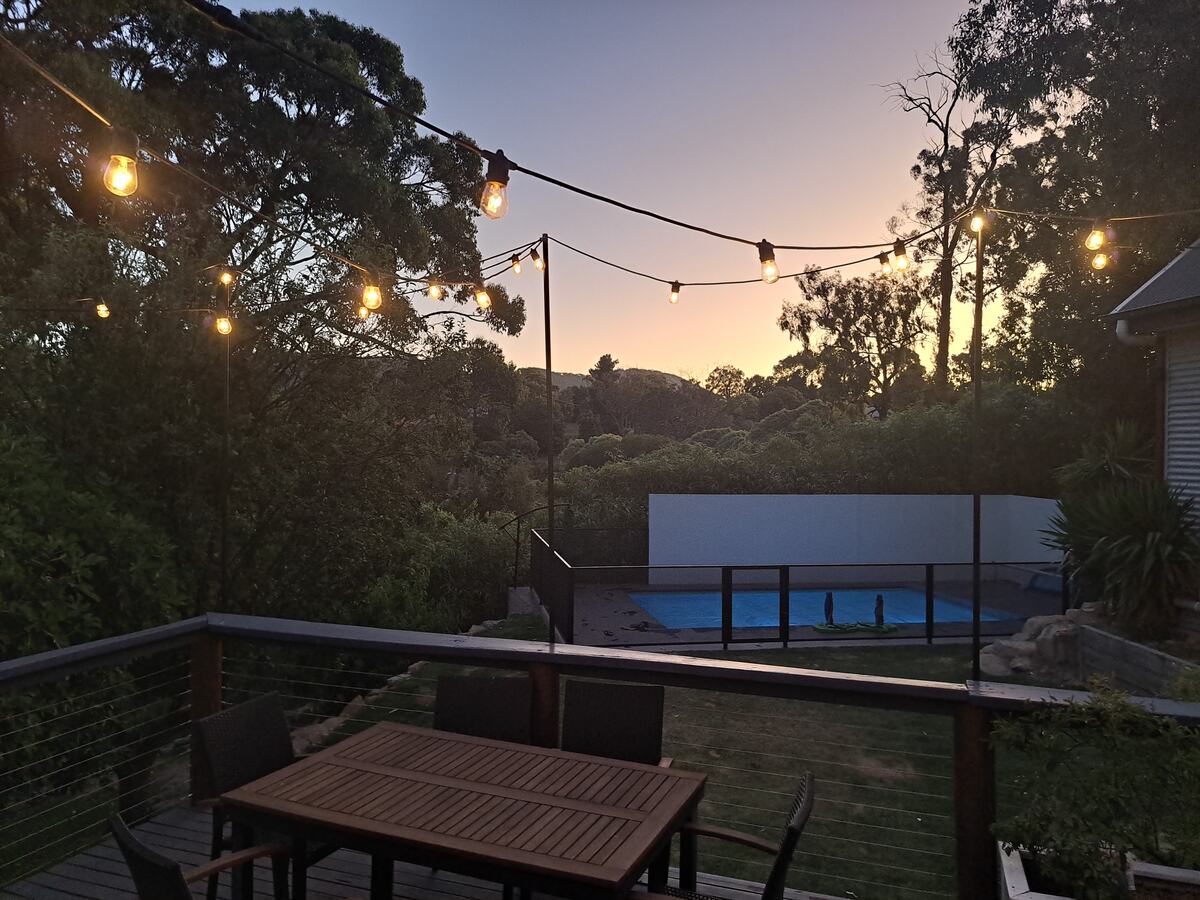 Pure Perf pool fencing on a deck at twilight with festoon lights, Melbourne