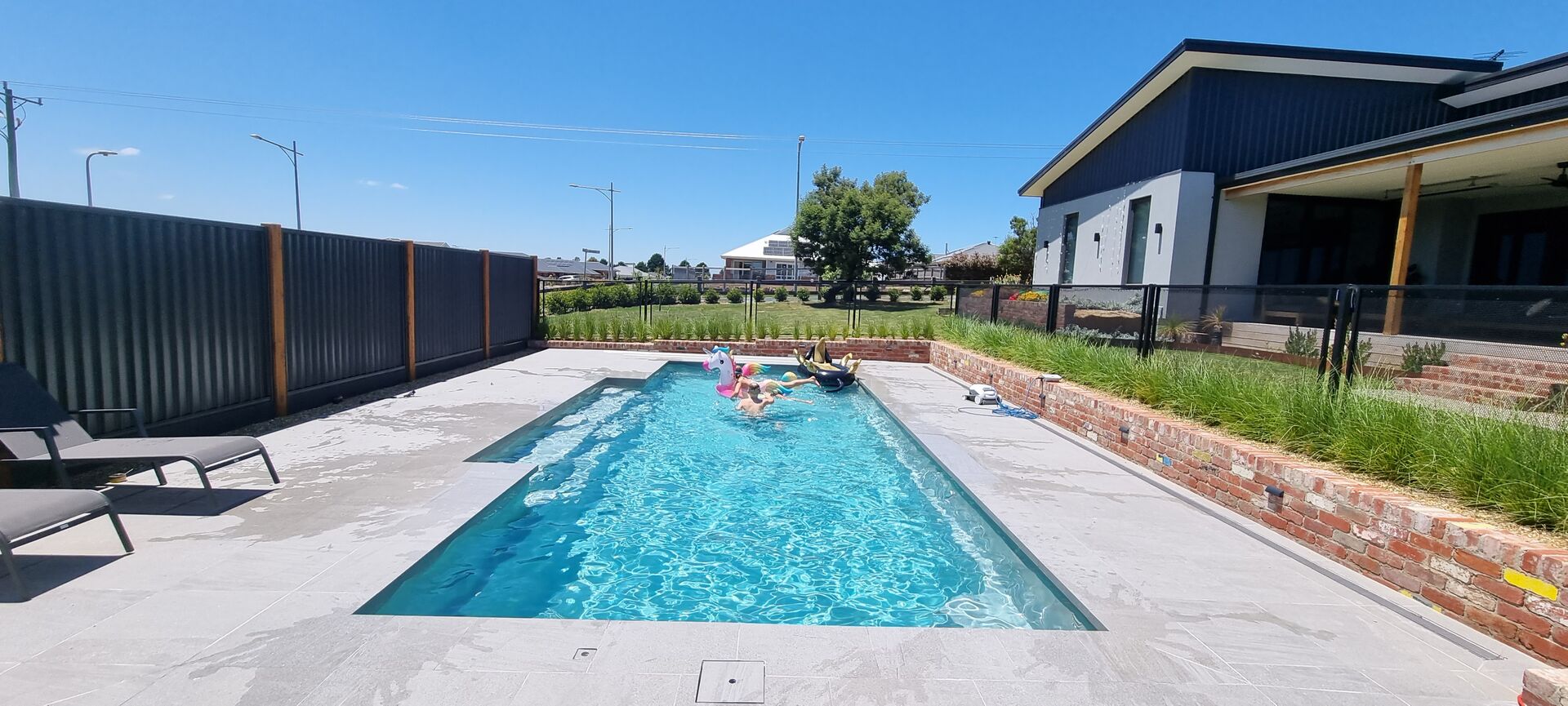 Pure Perf pool fencing in Textured Black along a long swimming pool with sun lounges, Victoria